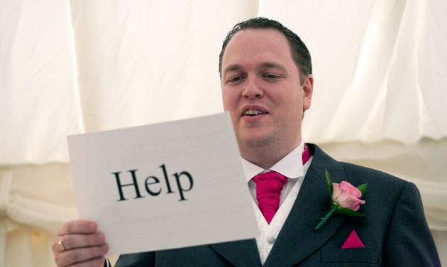 groom holding words to his speech with the word help written on the back