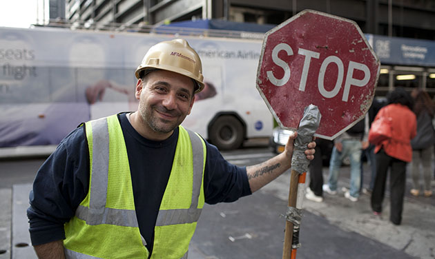 natural portrait of construction worker holding a stop sign on new york street