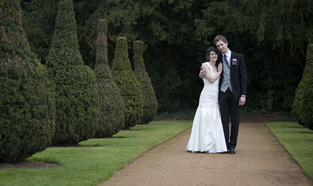 bride and groom in middle of avenue of bushes at Hylands House