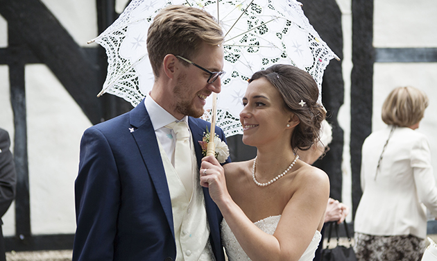 bride and groom under a white lace summer umbrella