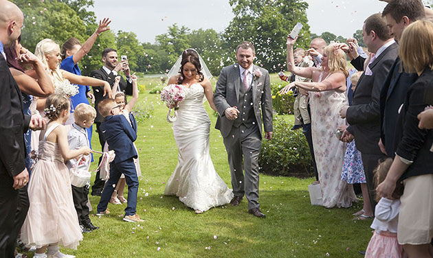 bride and groom walking between two lines of guests throwing confetti