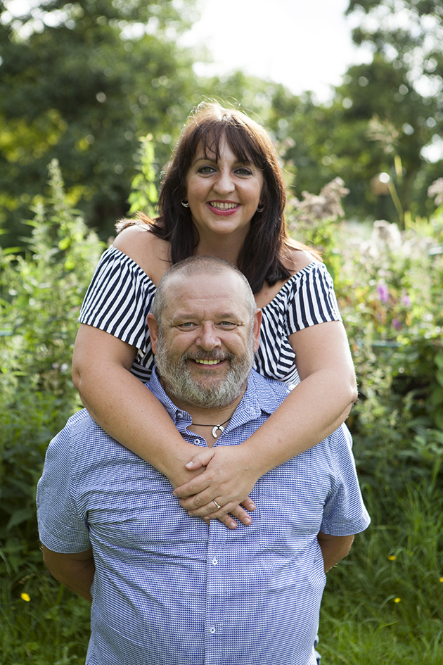 man kneeling with woman standing behind with arms around his neck