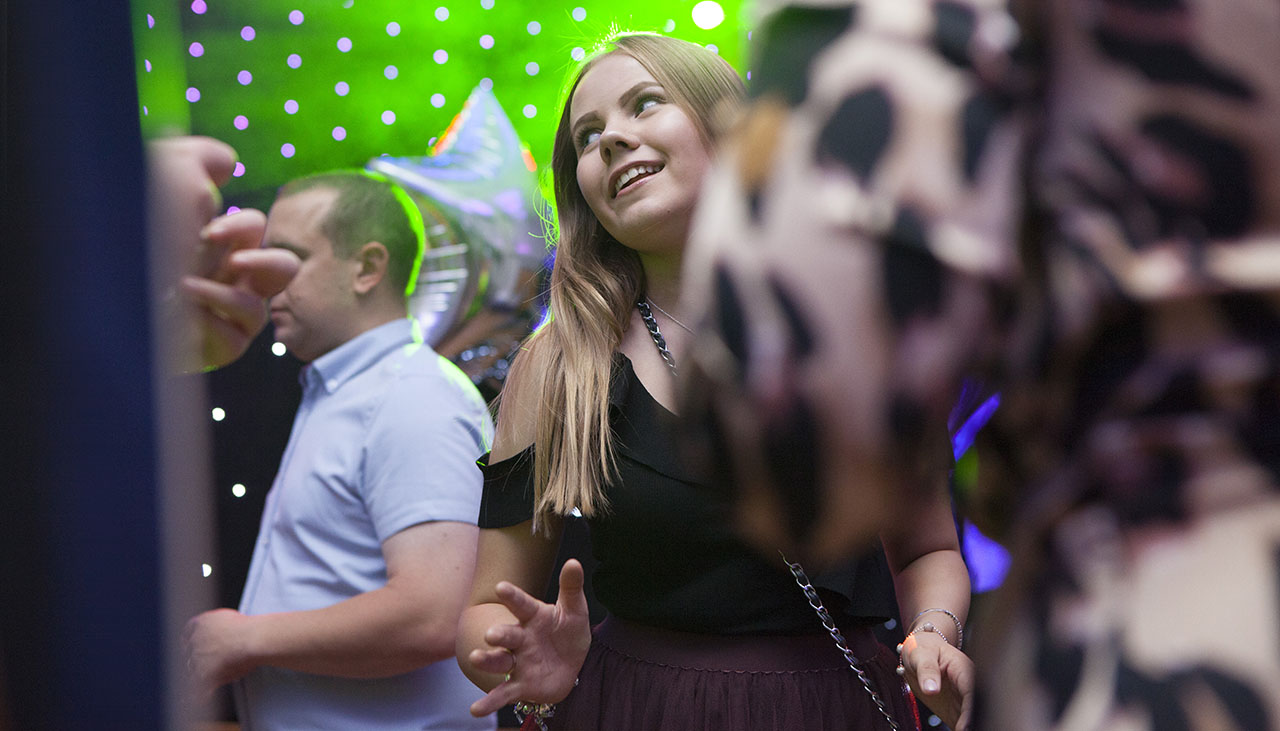 teenage girl on dance floor at party with green disco lights in background