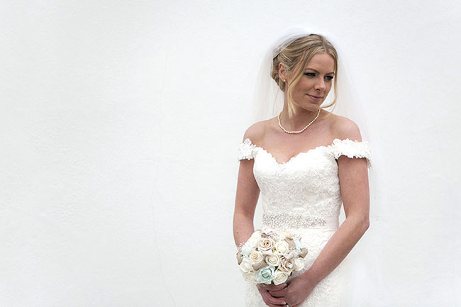 contemporary portrait of bride looking down to right against a white wall