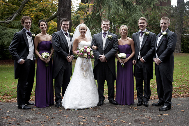 traditional wedding group photo of bride and groom with ushers and bridesmaids in church grounds