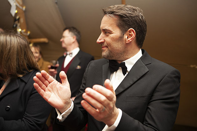 Man in black tie looking to the side and clapping