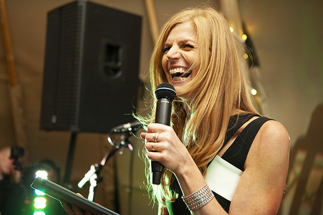 Woman on stage with a microphone and laughing