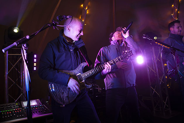 Rock band playing at a party on a stage covered with purple coloured lights