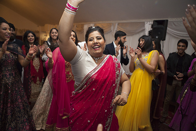 Woman in red sari dress on the dance floor with arms in the air