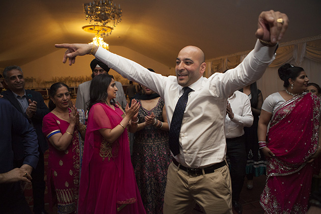man on dance floor with arms outstretched an Indian party 