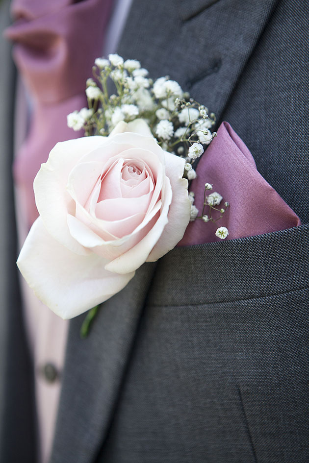 close up of groom's pink rose button hole
