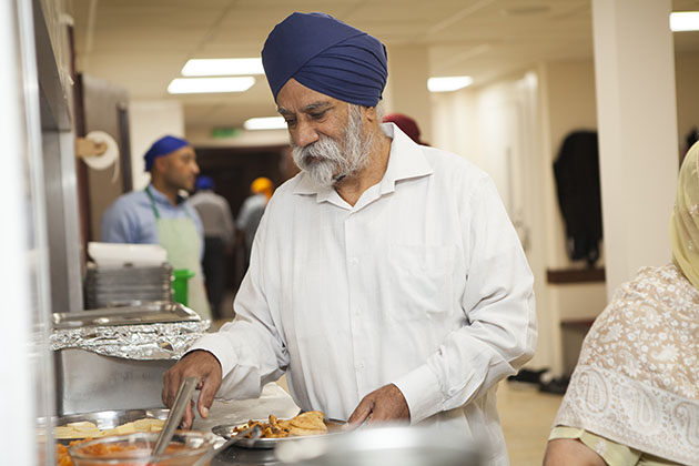 Indian man serving himself food at a Sikh kitchen