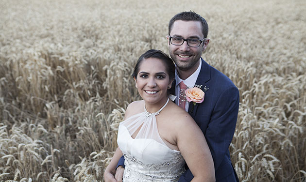Bride and groom standing together at Vaulty Manor with a wheat field in the background