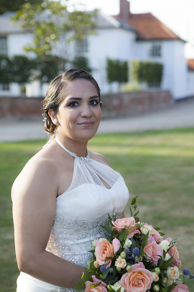 Portrait of bride holding a bouquet with Vaulty Manor in background
