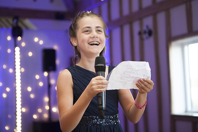 Young bridesmaid making a wedding speech with purple coloured lighting in the background