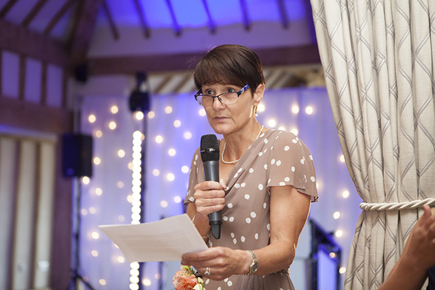 Woman making a wedding speech with purple coloured lights in background