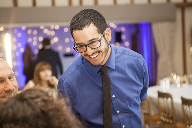 Wedding guest wearing a blue shirt talking to other guests