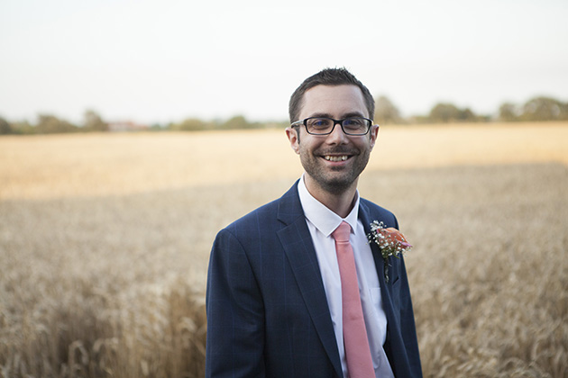 Relaxed portrait of groom with field of wheat in background