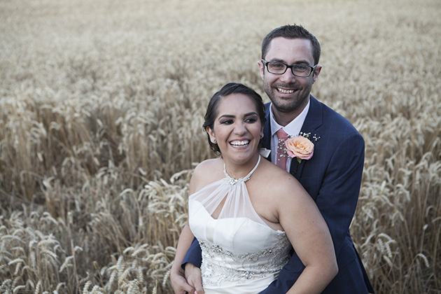 Fun portrait of bride and groom with a field of wheat in the background