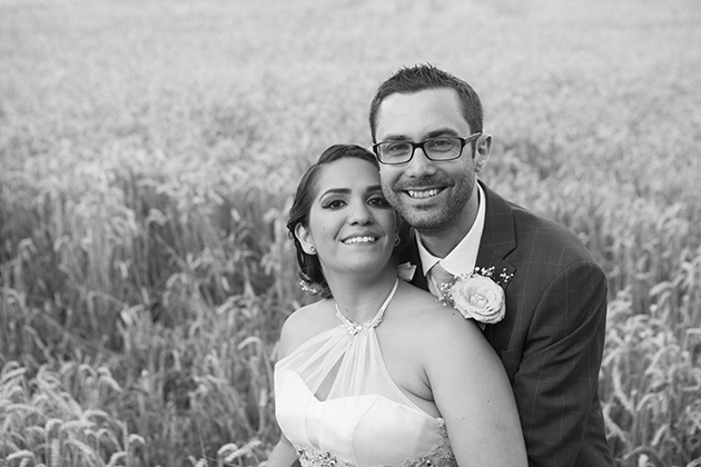Black and white portrait of bride and groom with a field of wheat in the background