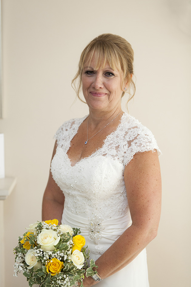 Portrait of bride at home holding bouquet of white and yellow flowers