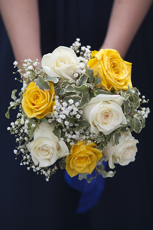 Hands held out holding a bouquet of yellow and white flowers