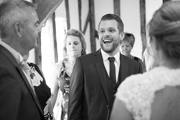 Wedding guest in receiving line looking at groom and laughing