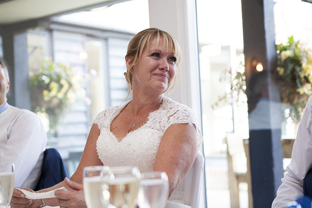 Emotional bride at top table during wedding speeches looking to the side