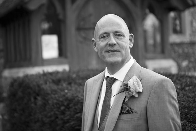 Natural black and white portrait of groom in church grounds