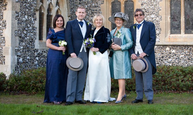 traditional wedding group photo of five people in church grounds