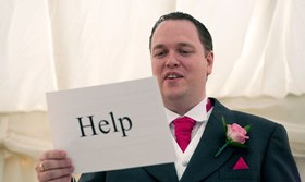 groom holding words to his speech with the word help written on the back
