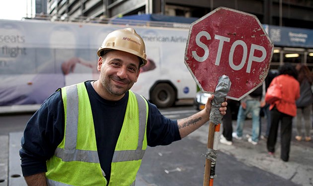 natural portrait of construction worker holding a stop sign on new york street