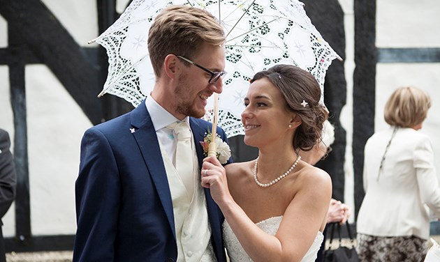 bride and groom under a white lace summer umbrella