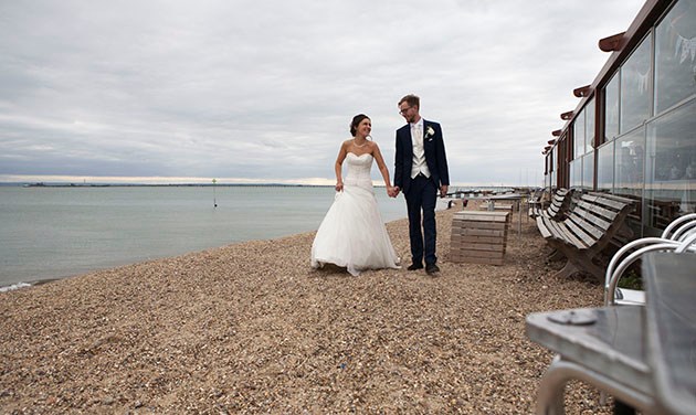 bride and groom walking hand in hand towards camera on Southend beach