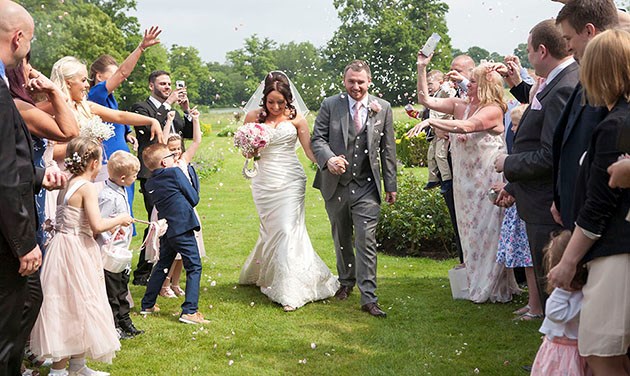 bride and groom walking between two lines of guests throwing confetti