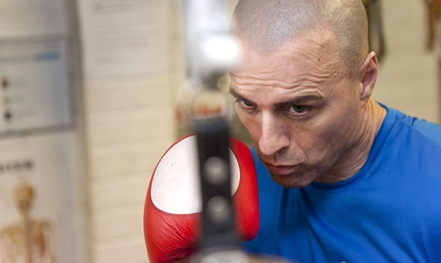 boxer wearing blue t-shirt and red boxing gloves punching a punch bag