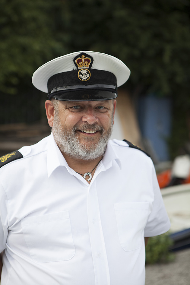 portrait of man in sailor uniform with boatyard in background