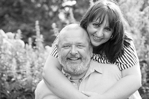 woman standing behind man with arms around his neck