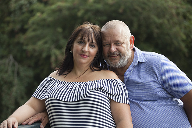 couple standing on bridge over river looking at camera