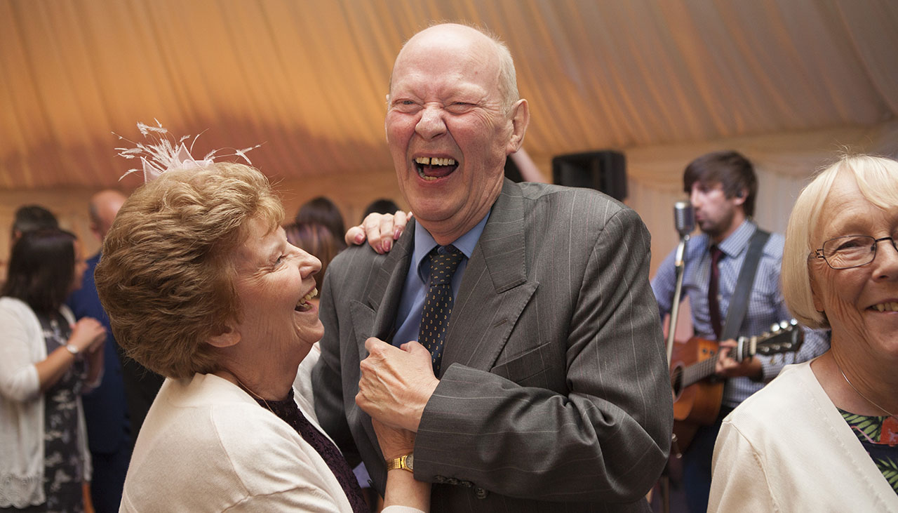 man and woman holding hands, dancing and laughing at a wedding reception party