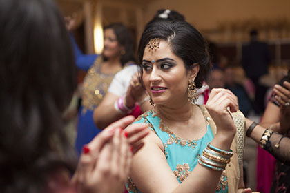 candid photo of a lady in traditional Indian dress with her friends on dance floor during a party