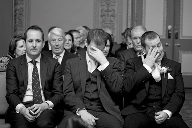 reportage style photo of three nervous men prior to wedding ceremony with hands to their faces