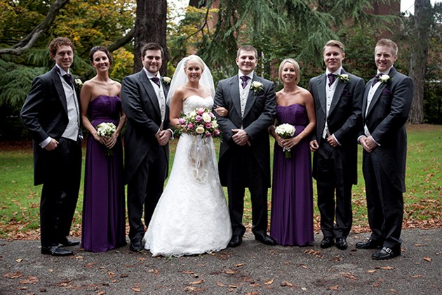 traditional wedding group photo of bride and groom with ushers and bridesmaids in church grounds