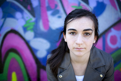 portrait of young girl against a bright pink and blue graffiti wall