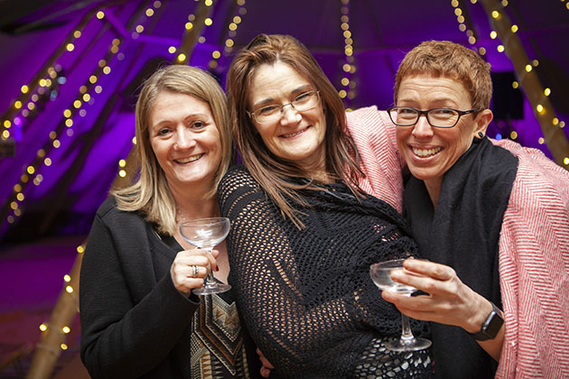 Three party guests looking at camera with sparkling lights in the background