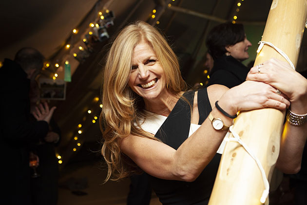 Woman holding onto a wooden post looking at camera and smiling