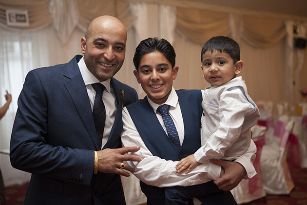 Informal portrait of father, teenage son and young child all looking at camera