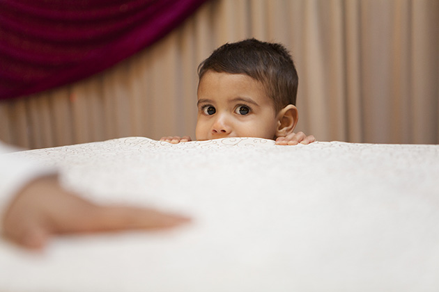 Young boy peering over a table and staring at the camera