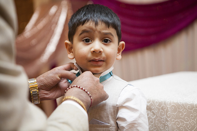 Young boy having a bow tie fastened by a parent