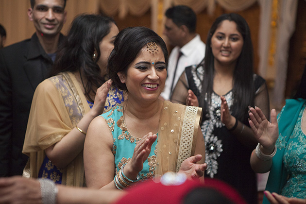 Woman in turquoise sari dress clapping hands and laughing